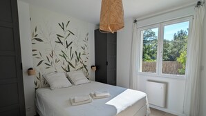 A bedroom with a bed, a window, a wall with a leaf pattern, and a hanging light fixture. - Villa Oïhana 4*, 5 suites, Heated pool, Beach 5 km (Labenne)