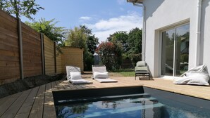 An outdoor swimming pool with wooden deck, lounge chairs, and a wooden fence. - Villa Oïhana 4*, 5 suites, Heated pool, Beach 5 km (Labenne)