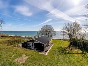 Una casa moderna con vista al mar, césped y un columpio.