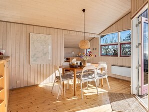 Un interior de madera con una mesa de comedor, sillas, una lámpara colgante y un mapa grande en la pared.