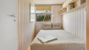 A bedroom with a bed, a window with a view, wooden walls, and a door. - "Stefan" - 50m from the sea by Interhome (Odder)