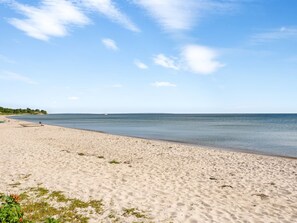 Une plage de sable fin, avec un ciel dégagé et une mer calme.