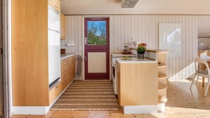 A modern kitchen with wooden cabinets, a central island, and a view through a door. - "Stefan" - 50m from the sea by Interhome (Odder)