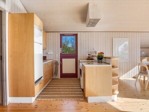 Una cocina moderna con armarios de madera, una isla central y vistas a través de una puerta.