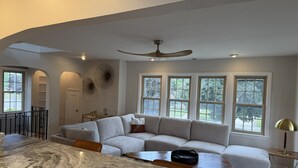 A modern living room with a sectional sofa, a marble dining table, and large windows. - Walk to the Waves and the Zoo Main St (Racine)