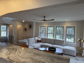 A modern living room with a sectional sofa, a marble dining table, and large windows. - Walk to the Waves and the Zoo Main St (Racine)