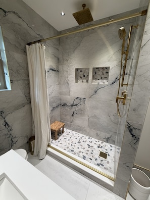 A bathroom with a marble shower, a wooden stool, and a glass-enclosed shower area. - Walk to the Waves and the Zoo Main St (Racine)