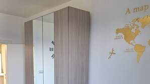 Ein modernes Wohnzimmer mit einem grauen Sofa, zwei runden Holztischen, einem großen Spiegel und einer Wandkarte.