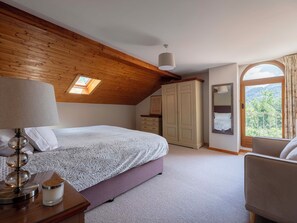 A bedroom with a sloped ceiling, a bed, a dresser, a mirror, and a window with a view of greenery. - Chalet Nivicare for 14 pax
Walking distance to ski gondola and village center (Saint-Gervais-les-Bains)