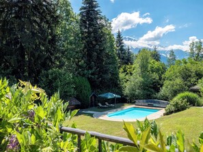 A backyard with a swimming pool, surrounded by lush greenery and trees. - Chalet Nivicare for 14 pax
Walking distance to ski gondola and village center (Saint-Gervais-les-Bains)