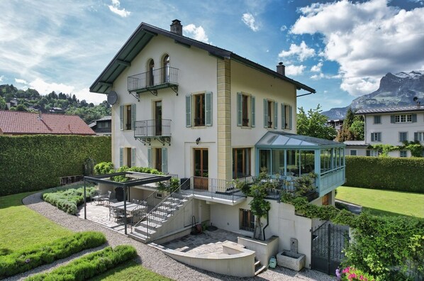 Ein zweistöckiges Haus mit Balkon, Wintergarten und einem gepflegten Garten.