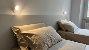 Een slaapkamer met twee bedden, elk voorzien van een kussen en een wandlamp.