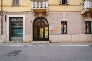 Ein Gebäude mit großem Bogenportal, einem Balkon mit schmiedeeisernen Geländern und einem kleinen Fenster mit Rollo.