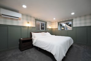 Un dormitorio con cama, mesita de noche, cómoda y dos luces fijadas a la pared.