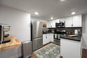 Una cocina moderna con electrodomésticos de acero inoxidable, armarios blancos y una alfombra estampada.