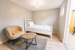 Ein Schlafzimmer mit einem Bett, einem Sessel und einem kleinen Tisch.
