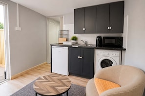 Eine kompakte Küche mit Waschmaschine, Mikrowelle und kleinem Kühlschrank.