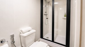 Ein modernes Badezimmer mit Toilette, einer Dusche mit Glasabtrennung und einem weißen Waschbecken.