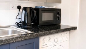 Eine Küche mit einer schwarzen Kaffeemaschine, einer Mikrowelle und einem Geschirrspüler.