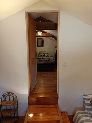 Un escalier étroit en bois mène à une chambre à coucher qui contient un lit et une table de chevet.