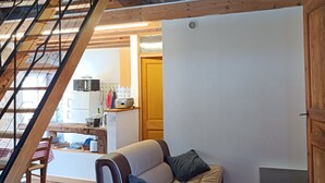 Ein Loft-Zimmer mit einer Holztreppe, einem Sofa, einem Sessel und einem roten Teppich.