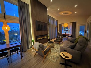 A modern living room with a fireplace, a dining area, and a view of the outdoors.