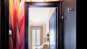 A hallway leading to a bedroom with a bed, a nightstand, and a window with curtains. - Cocon Heliot hypercentre Toulouse métro A&B Jean Jaurès - Pl. Wilson - Capitole (Toulouse)