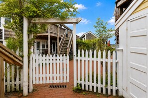 A white picket fence, a brick pathway, and a wooden staircase leading to a porch. - *NEW* Waterfront Studio - Bay Views, Steps to Comm St (Provincetown)