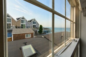 A view of a coastal building complex with multiple structures, a wooden deck, and a clear view of the sea. - *NEW* Waterfront Studio - Bay Views, Steps to Comm St (Provincetown)