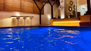 An indoor swimming pool with a wooden ceiling, bar stools, and a glass wall with decorative plates. - Villa & Pool Cascada - Tequesquitengo Lake View (Tequesquitengo)