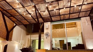 An indoor pool area with a thatched roof, a seating area, and a large window. - Villa & Pool Cascada - Tequesquitengo Lake View (Tequesquitengo)