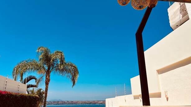 A pool with clear water, a palm tree, and a white building with a black column. - Villa & Pool Cascada - Tequesquitengo Lake View (Tequesquitengo)