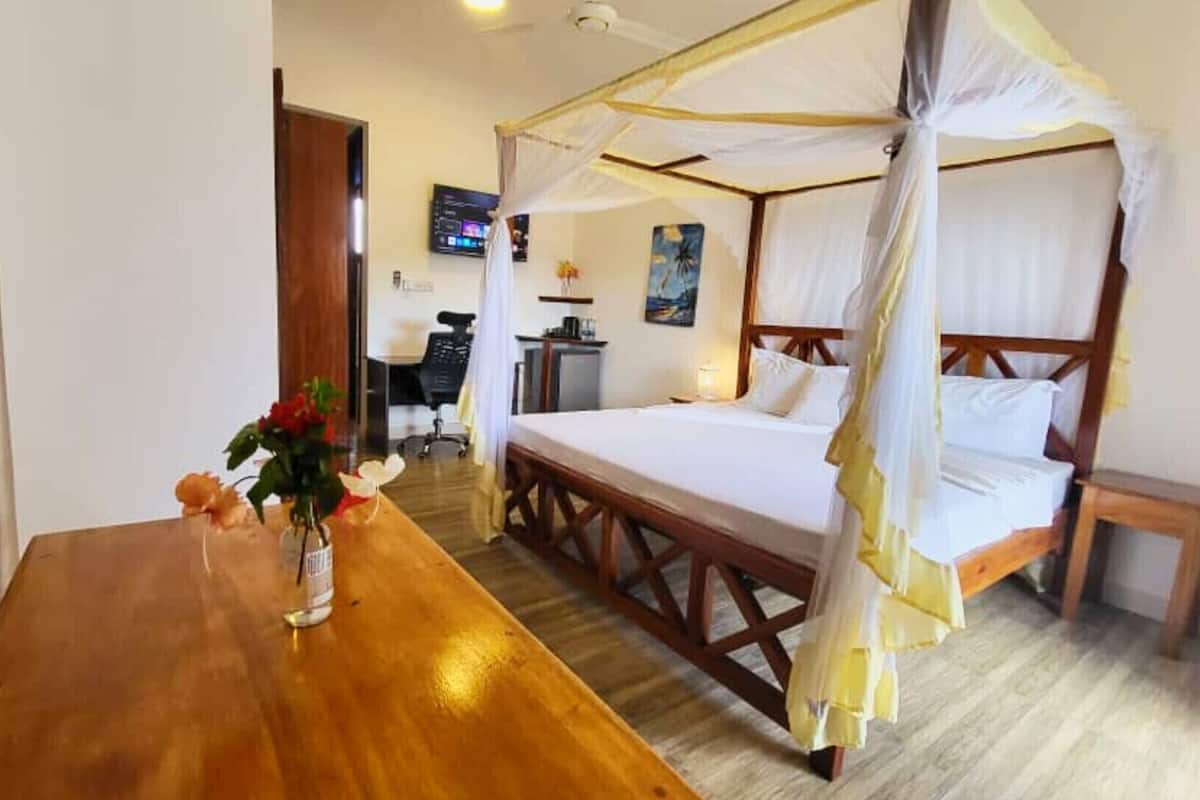 Una habitación con una cama con dosel, un escritorio de madera y una silla.