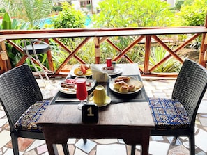 A table with breakfast items, a red cup, and a number sign on a chair. - Mimi na Wewe Bungalows Hotel (Nungwi)