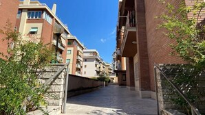 A narrow residential street with multi-story buildings, balconies, and a clear blue sky. - Vatican Living Rome (Rome)