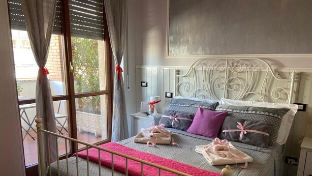A bedroom with a bed, curtains, a window, and a metal headboard. - Vatican Living Rome (Rome)