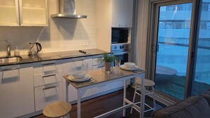 Una cocina moderna con una isla central, electrodomésticos de acero inoxidable y vistas al exterior a través de un amplio ventanal.
