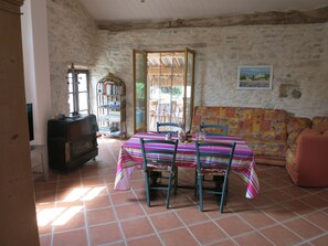A room with a tiled floor, a table with chairs, a sofa, a bookshelf, and a television. - Country house.  Alpes de Haute-Provence (Clumanc)