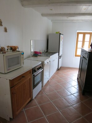 A kitchen with white cabinets, a microwave, an oven, a sink, and a refrigerator. - Country house.  Alpes de Haute-Provence (Clumanc)