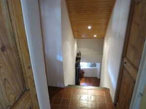 A narrow hallway with wooden walls and a tiled floor leading to a bedroom with a bed and a nightstand. - Country house.  Alpes de Haute-Provence (Clumanc)
