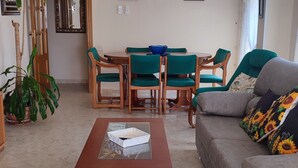 Una sala de estar con ventilador de techo, una mesa de comedor con sillas, un sofá y una mesa baja.