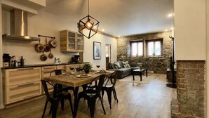 A spacious kitchen with wooden flooring, a dining area with a wooden table and chairs, and a stone accent wall. - A lovely apartment with Victorian charm (Québec)