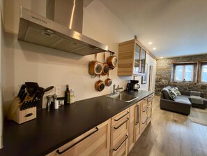 Eine moderne Küche mit Holzausbau, einer Edelstahl-Dunstabzugshaube und einer Steinwand.