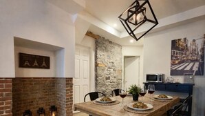 A dining area with a wooden table, black chairs, a stone wall, and a hanging light fixture. - A lovely apartment with Victorian charm (Québec)