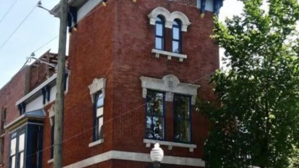 A red brick building with a corner entrance, a visible street sign, and a small balcony. - A lovely apartment with Victorian charm (Québec)