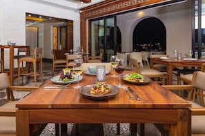 Ein Restaurant mit Holztischen und -stühlen, das Gerichte mit Weingläsern serviert.