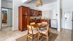 Eine Küche mit Holzausstattung, einem Esstisch mit Stühlen, einer Hängeleuchte und einem Kühlschrank.