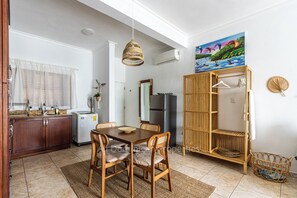 Uma cozinha com mesa de jantar, cadeiras, geladeira e um armário de madeira.