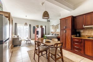 Una cocina amplia con armarios de madera, una mesa de comedor con sillas y un refrigerador moderno.