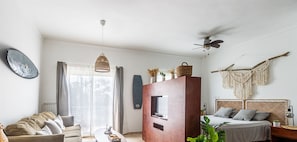 Una sala de estar moderna con un sofá, una mesa de centro, un televisor y una cama con cabecera.
